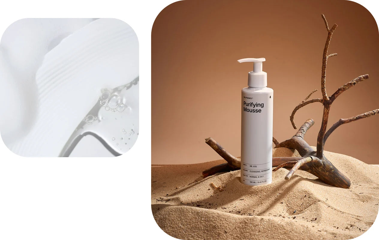 White bottle labeled 'Purifying Mousse' on a sandy surface with desert plants.